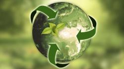 green globe with green recycling arrows circling globe on a blurred green nature backgound
